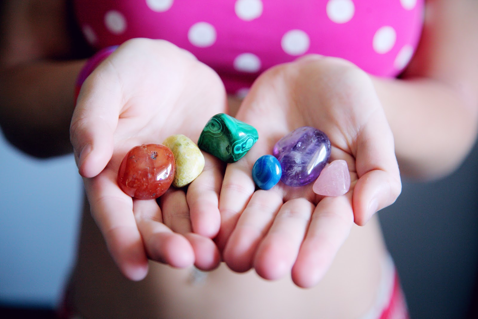 A photograph of a child holding colourful stones in their hands.