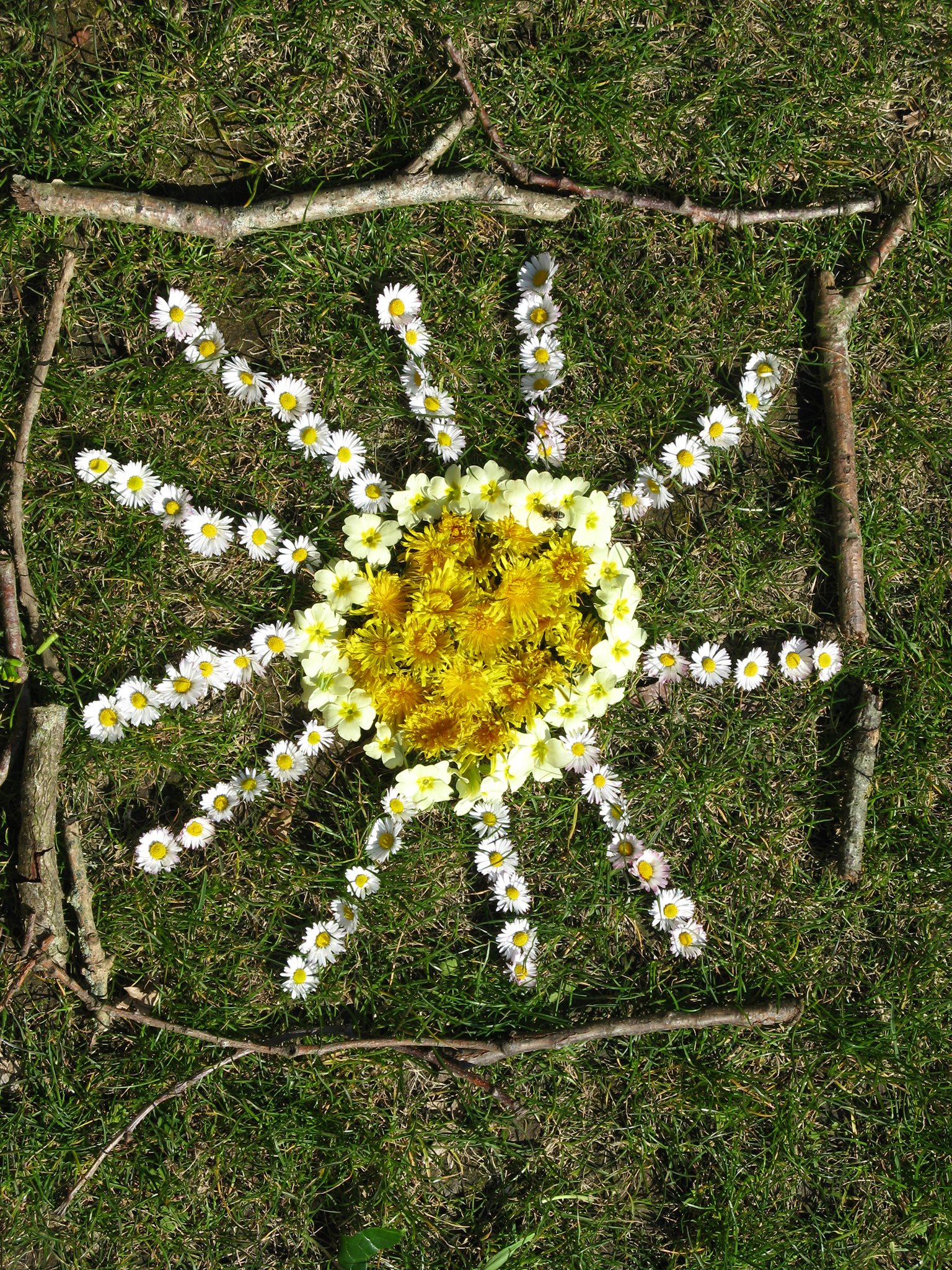 Flowers arranged artfully to make one large flower on the ground.