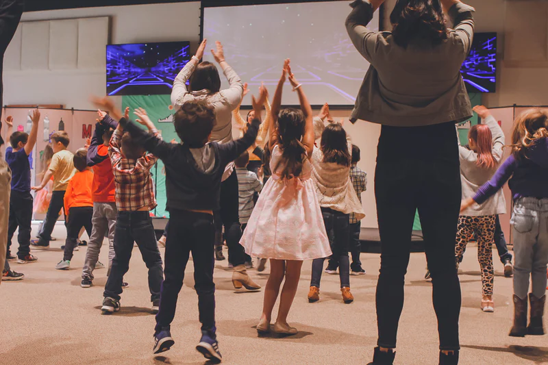 A group of children dancing with their arms above their heads.