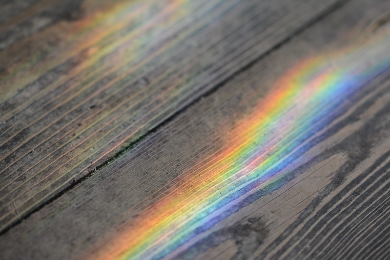 A rainbow reflected on hardwood floor.