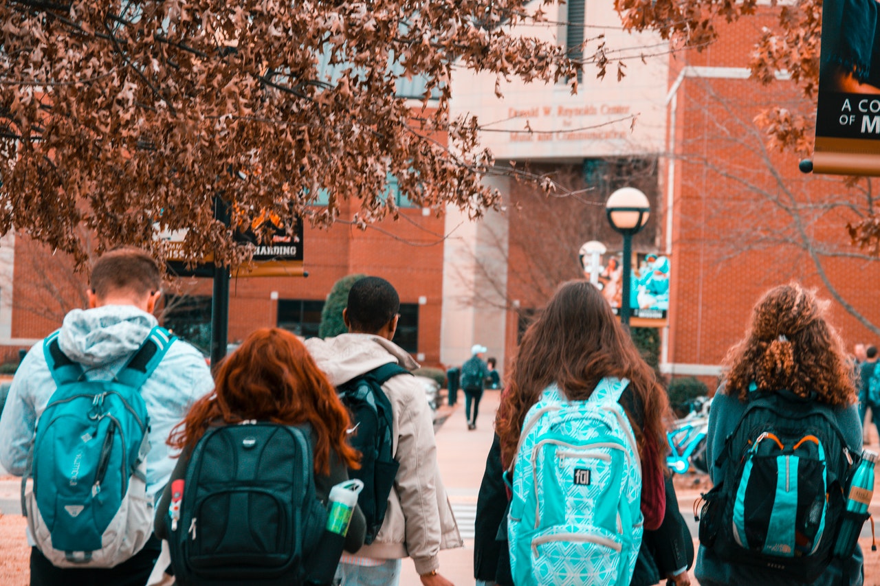 Students wearing backpacks standing in a line.