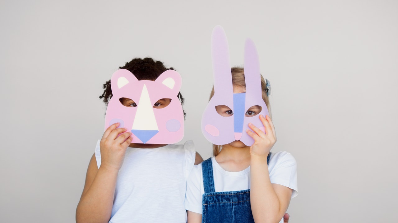 An image of two children wearing animal themed masks they made themselves.