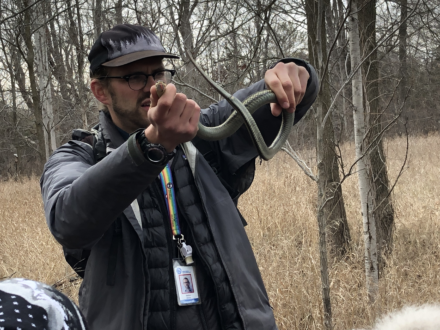 Outdoor educator holds snake in two hands.