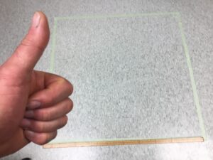 a photo of a square meter made of green tape on the floor - and a thumbs up